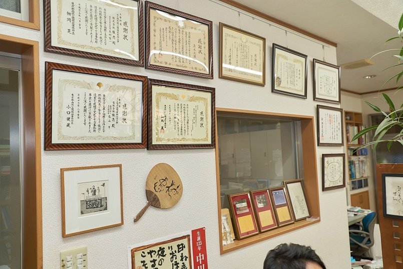 たくさんの賞状と記念品が飾られたオフィス