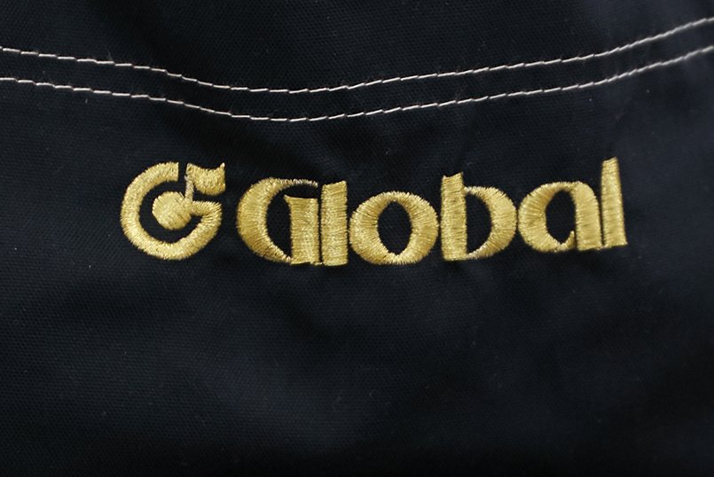 エプロンの正面に「G」の文字と八分音符をかたどったロゴマークを刺繍